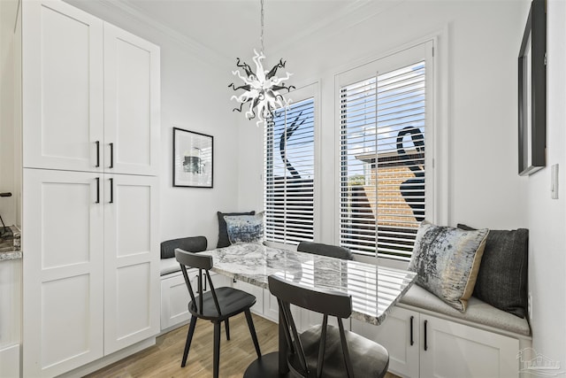 dining space featuring ornamental molding, an inviting chandelier, and light hardwood / wood-style floors