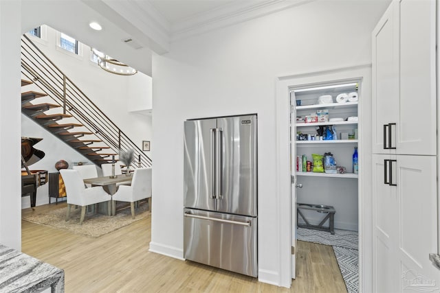 kitchen with ornamental molding, high end fridge, white cabinets, and light wood-type flooring