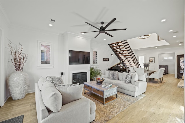 living room with ornamental molding, ceiling fan, and light hardwood / wood-style flooring