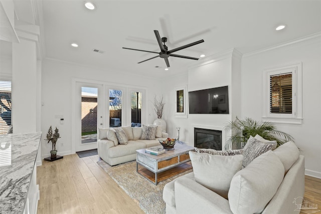 living room with crown molding, ceiling fan, light wood-type flooring, and french doors