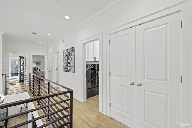 corridor featuring ornamental molding, washer and dryer, and light wood-type flooring