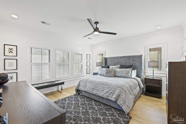 bedroom featuring multiple windows, ornamental molding, and light wood-type flooring