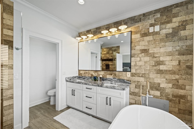 bathroom featuring crown molding, a bathing tub, vanity, wood-type flooring, and toilet