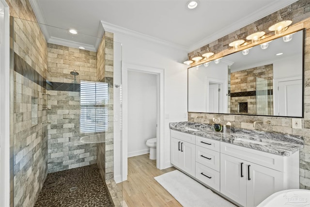 bathroom with vanity, hardwood / wood-style floors, ornamental molding, and tiled shower