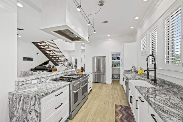 kitchen featuring white cabinetry, high end appliances, light stone countertops, and crown molding