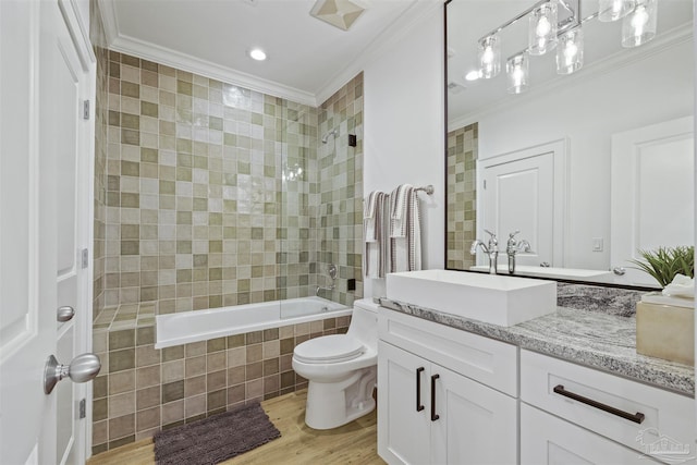 full bathroom featuring crown molding, vanity, wood-type flooring, toilet, and tiled shower / bath