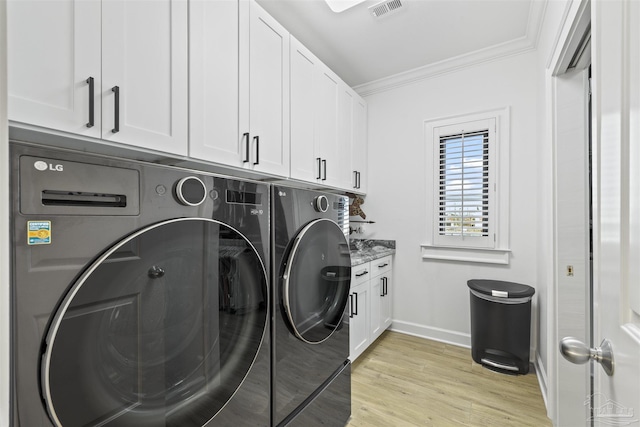 laundry room featuring crown molding, cabinets, washer and dryer, and light wood-type flooring