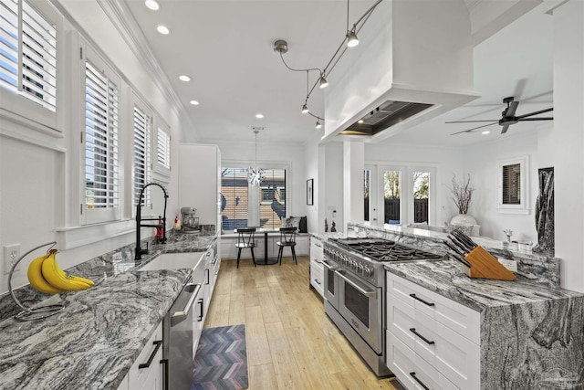 kitchen featuring stone countertops, decorative light fixtures, island range hood, appliances with stainless steel finishes, and white cabinets