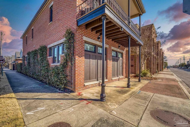 property exterior at dusk featuring a balcony