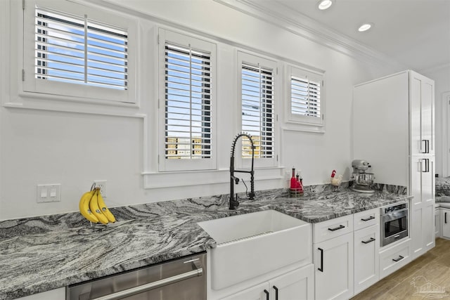 kitchen featuring white cabinetry, dark stone counters, dishwasher, and sink