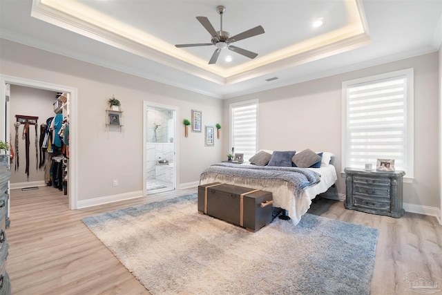 bedroom featuring connected bathroom, a spacious closet, multiple windows, and ceiling fan