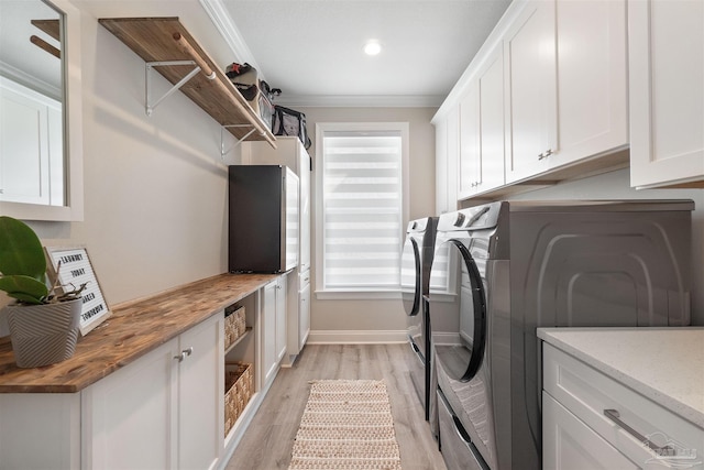 washroom featuring ornamental molding, washer and clothes dryer, cabinets, and light hardwood / wood-style floors