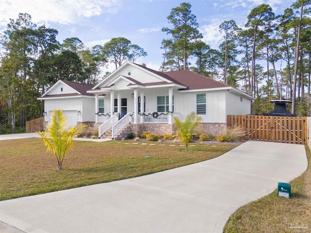 view of front of home with covered porch, a garage, and a front lawn