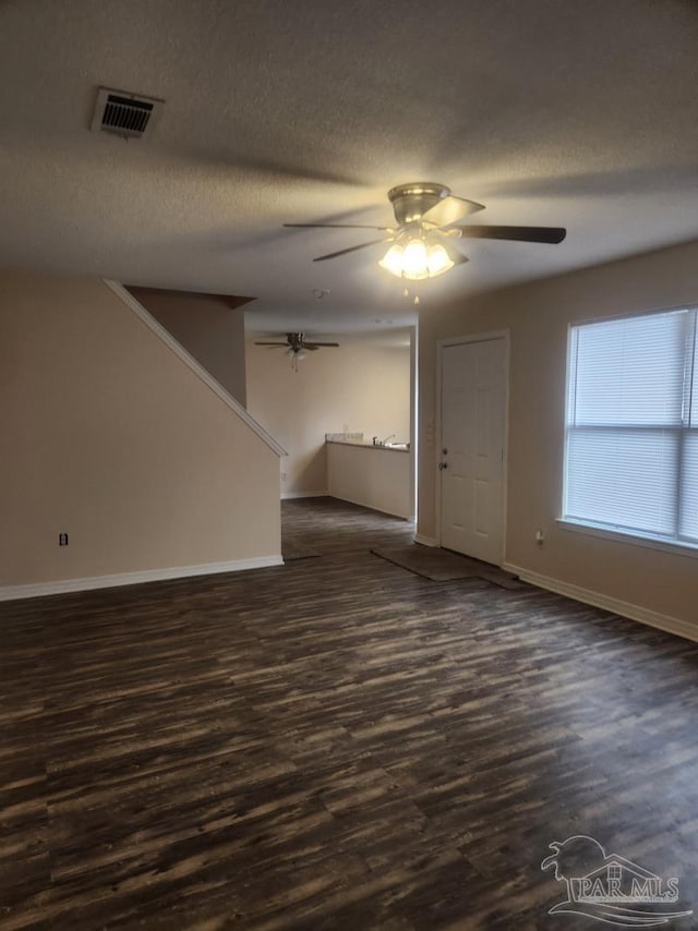 spare room with dark wood-type flooring, ceiling fan, and a textured ceiling