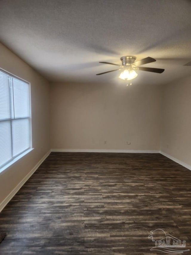 empty room with ceiling fan, dark wood-type flooring, and a textured ceiling