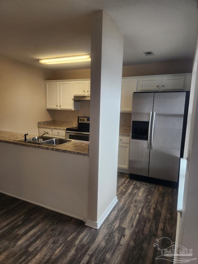 kitchen featuring dark stone countertops, dark wood-type flooring, stainless steel appliances, and white cabinets