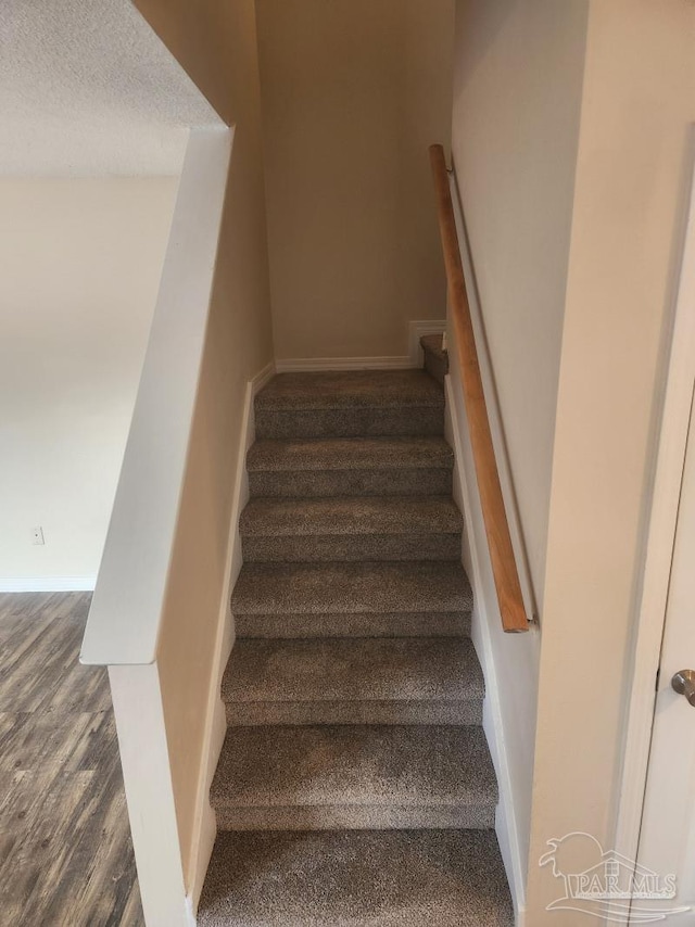 stairs with hardwood / wood-style floors and a textured ceiling