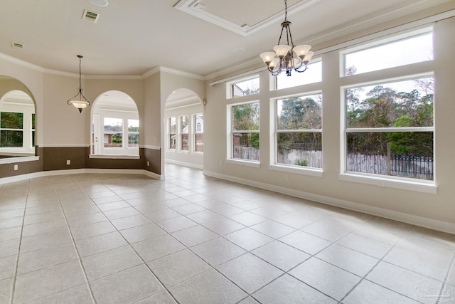 tiled spare room featuring ornamental molding and a chandelier