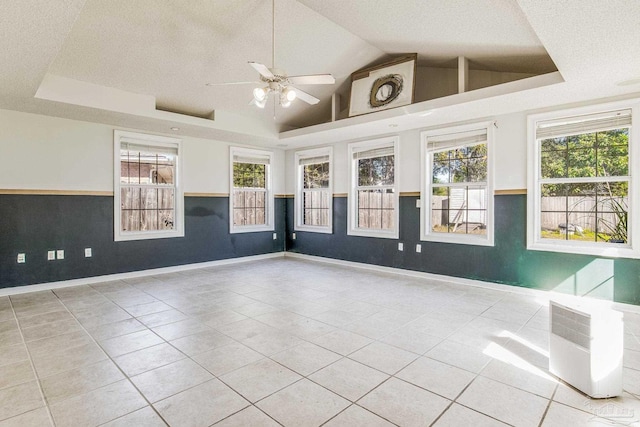 empty room with ceiling fan, light tile patterned floors, a textured ceiling, and vaulted ceiling