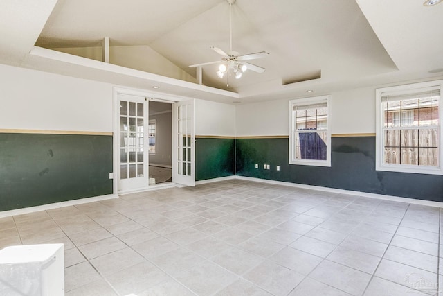 empty room featuring ceiling fan, light tile patterned flooring, vaulted ceiling, and french doors