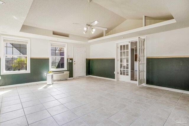 tiled spare room featuring french doors, a raised ceiling, vaulted ceiling, ceiling fan, and a textured ceiling