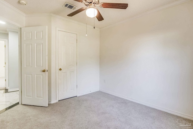 unfurnished bedroom featuring ceiling fan, crown molding, light colored carpet, and a textured ceiling