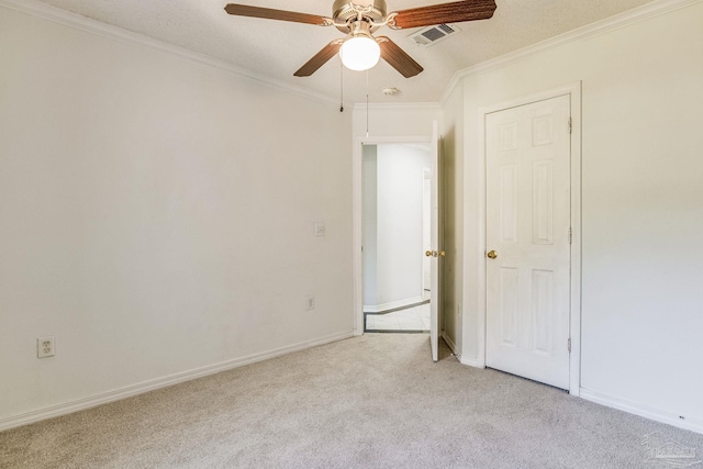 carpeted spare room with ceiling fan, ornamental molding, and a textured ceiling