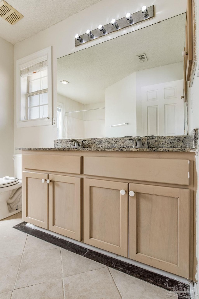 bathroom featuring walk in shower, vanity, a textured ceiling, tile patterned flooring, and toilet