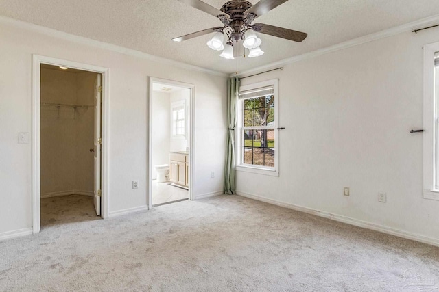 unfurnished bedroom featuring ensuite bathroom, ceiling fan, a spacious closet, and light carpet