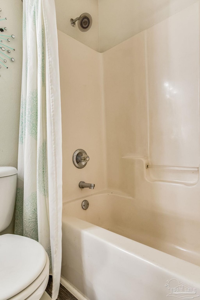 bathroom featuring shower / bath combo with shower curtain and toilet