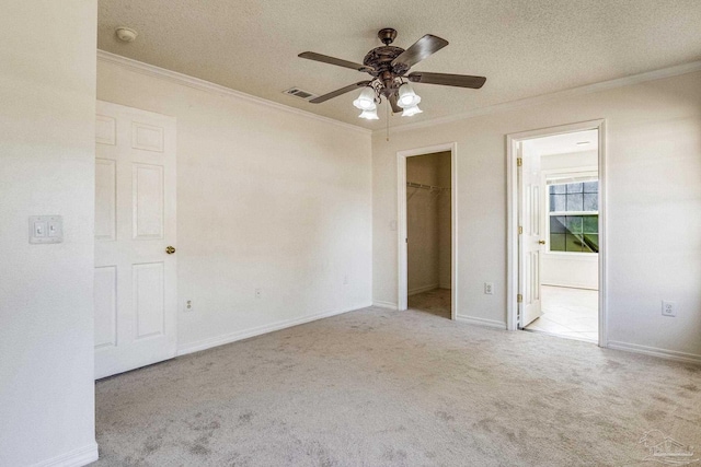 carpeted empty room featuring ceiling fan, a textured ceiling, and ornamental molding