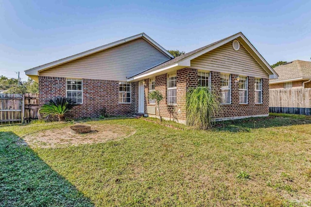 back of property featuring a fire pit and a lawn