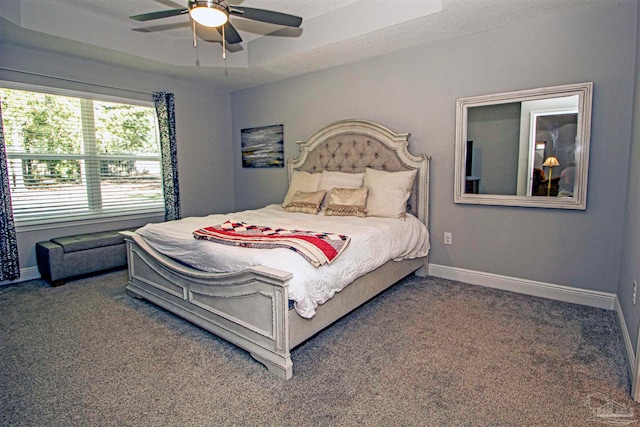 bedroom featuring ceiling fan, dark carpet, and a textured ceiling