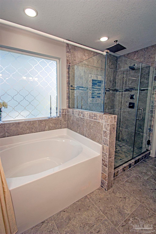 bathroom featuring plus walk in shower and a textured ceiling