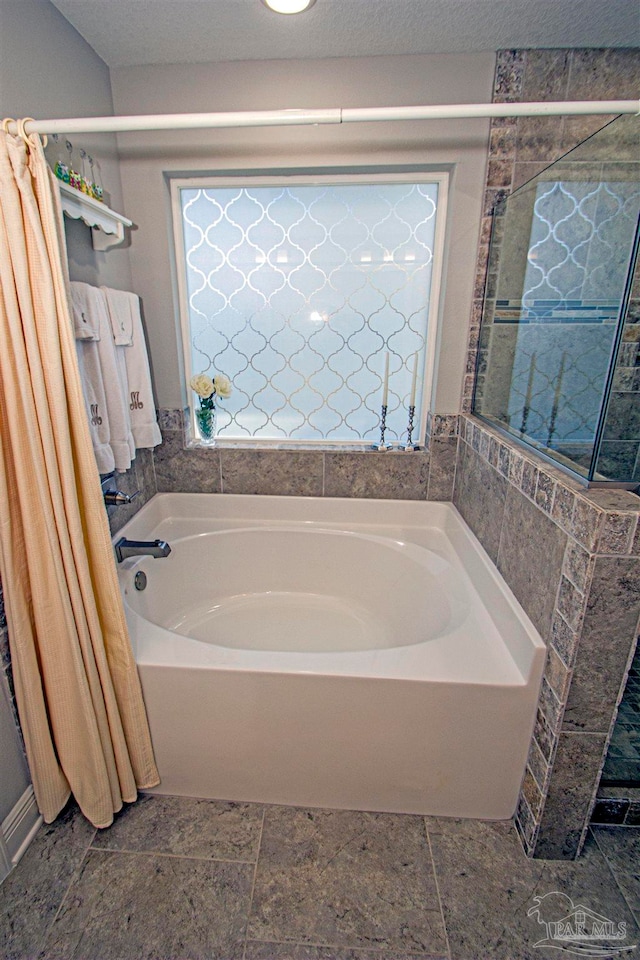 bathroom with a textured ceiling and a tub