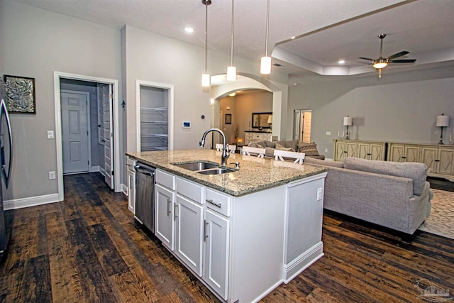 kitchen with light stone countertops, a kitchen island with sink, sink, decorative light fixtures, and white cabinets