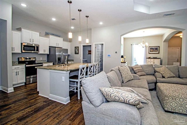 kitchen featuring white cabinets, dark hardwood / wood-style floors, a kitchen island with sink, and appliances with stainless steel finishes