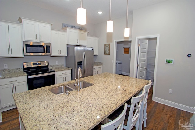 kitchen with appliances with stainless steel finishes, a kitchen island with sink, sink, pendant lighting, and white cabinets