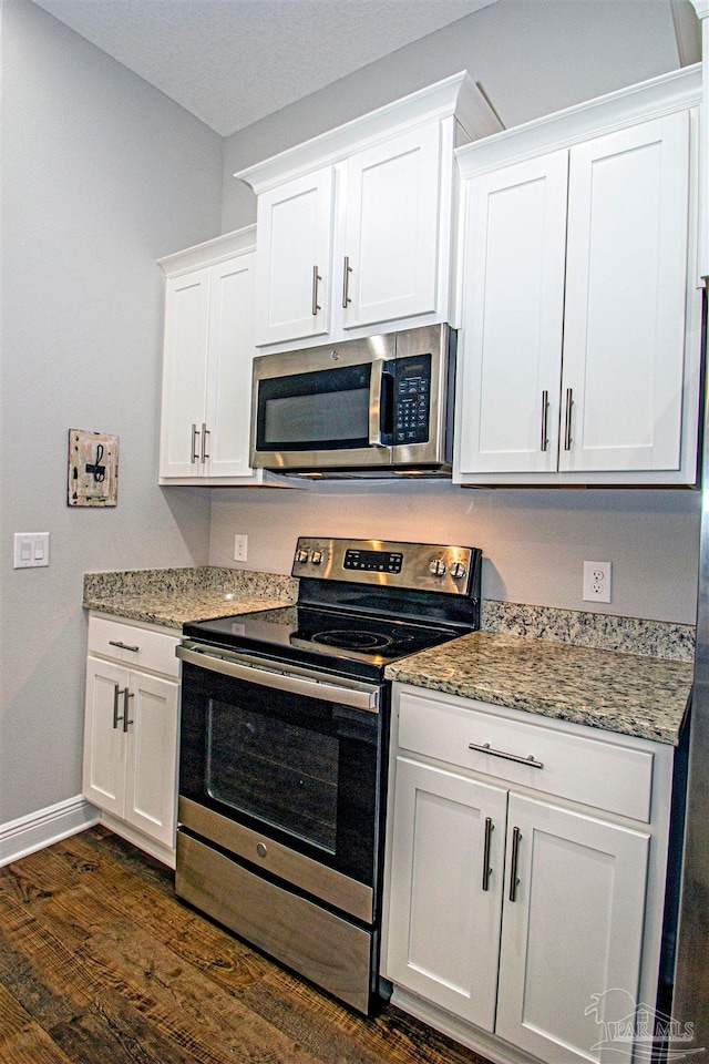 kitchen featuring white cabinetry, dark wood-type flooring, light stone counters, and appliances with stainless steel finishes