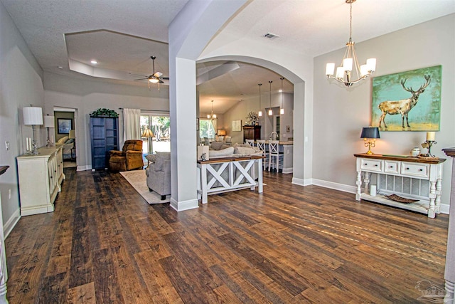 kitchen with pendant lighting, ceiling fan with notable chandelier, dark wood-type flooring, and a textured ceiling