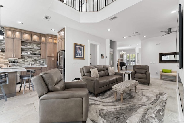 living room with ceiling fan with notable chandelier, sink, and light tile patterned floors