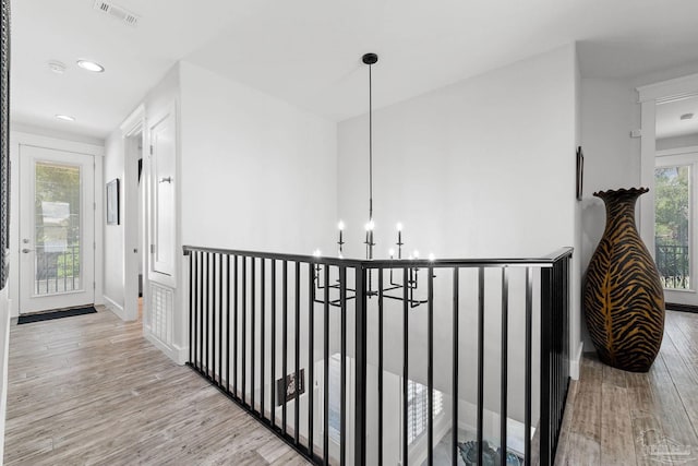 corridor featuring light wood-type flooring and a notable chandelier