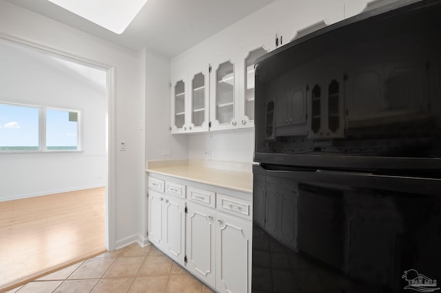 825 Bayshore Dr Unit 1206, Pensacola, FL 32507 - kitchen featuring glass insert cabinets, white cabinets, light countertops, light tile patterned flooring, and baseboards