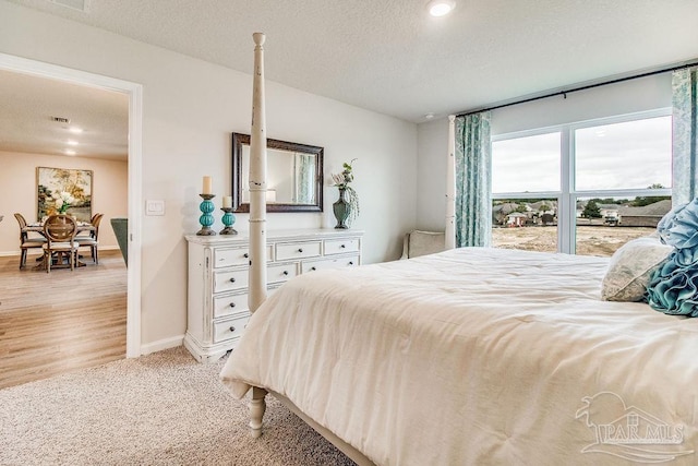 bedroom featuring light colored carpet and a textured ceiling