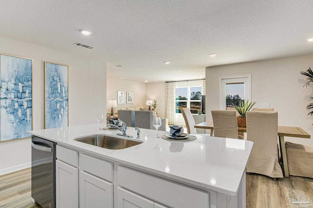 kitchen with sink, a kitchen island with sink, dishwasher, light hardwood / wood-style floors, and white cabinets