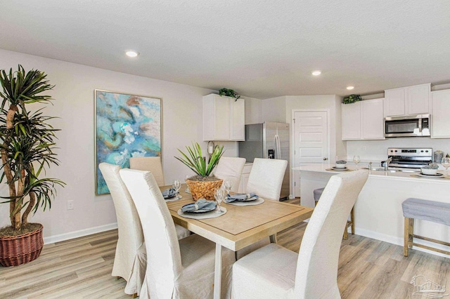 dining space featuring light hardwood / wood-style flooring and a textured ceiling