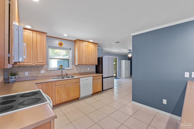 kitchen featuring white appliances, a sink, visible vents, decorative backsplash, and crown molding