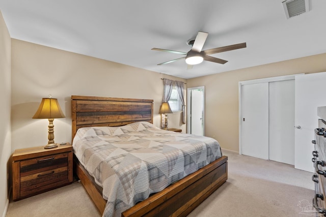 bedroom with light carpet, a ceiling fan, visible vents, and a closet