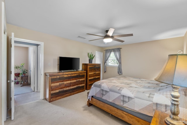 bedroom with a ceiling fan, visible vents, light carpet, and light tile patterned floors