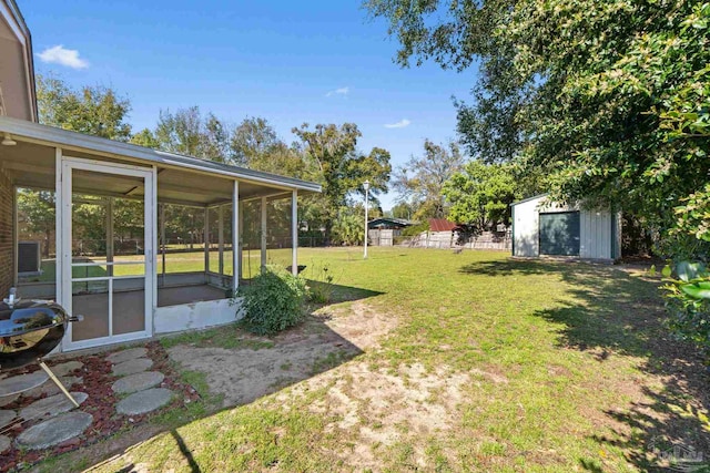 view of yard featuring a storage shed, an outbuilding, fence, and a sunroom